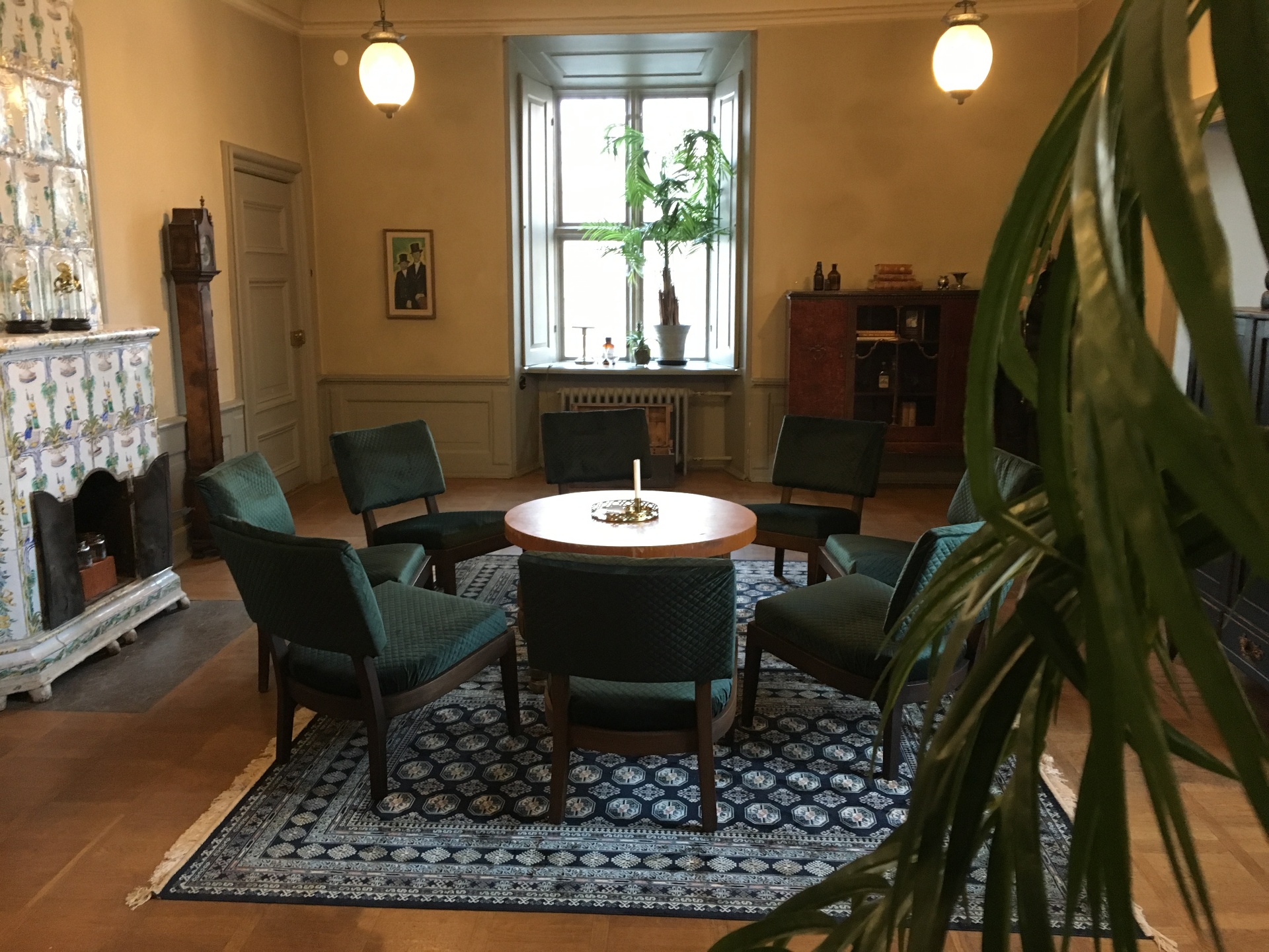 Salong med gröna sammetsfåtöljer och kakelugn