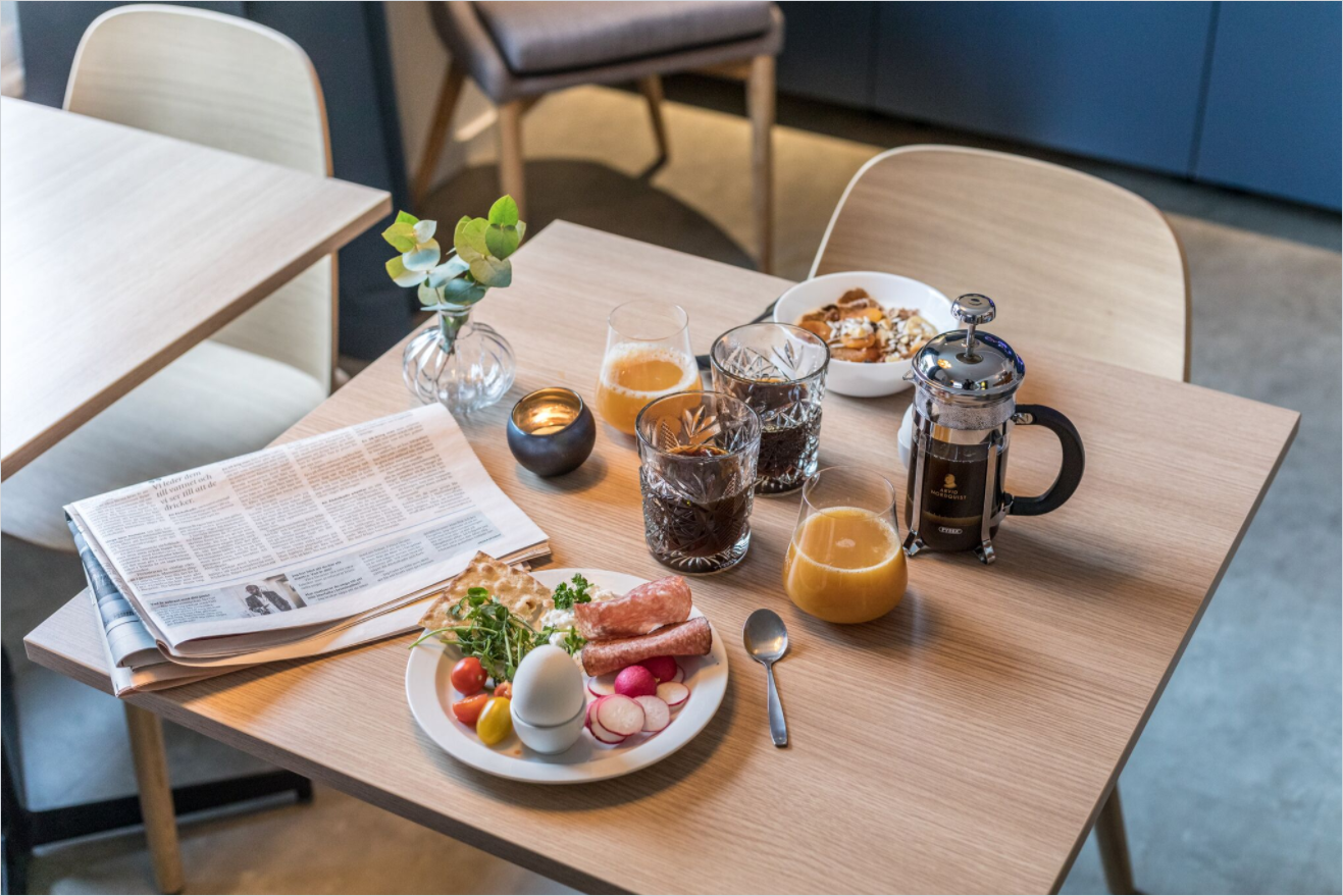 Frukostbricka på ekbord med tidning och French press