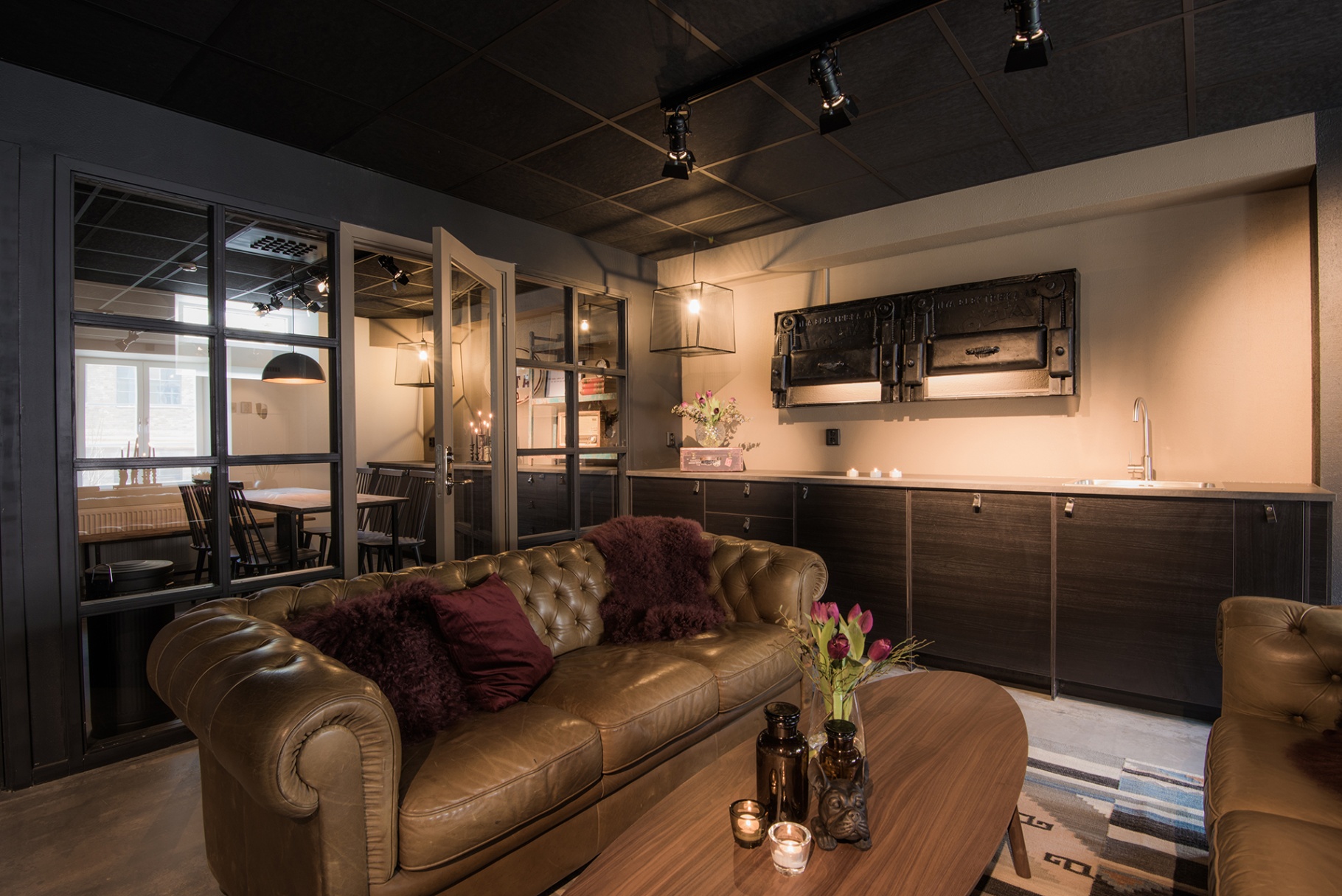 Loungehörn med chesterfield, industripendlar och gamla brännluckor på väggen