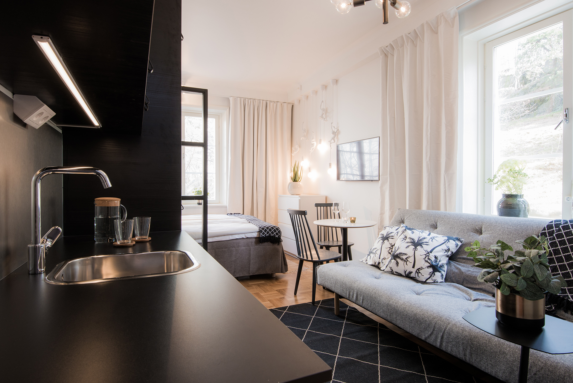 Ap-rummet 211 — svart pentry, bäddsoffa, säng och matplats i ett rum